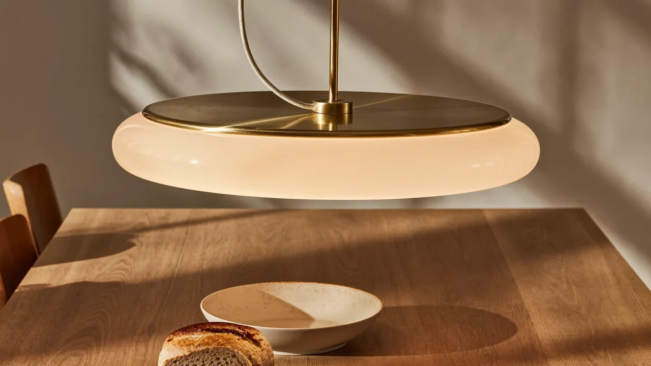 Mosiężna lampa wisząca ze szkłem opalowym nad dębowym stołem jadalnianym