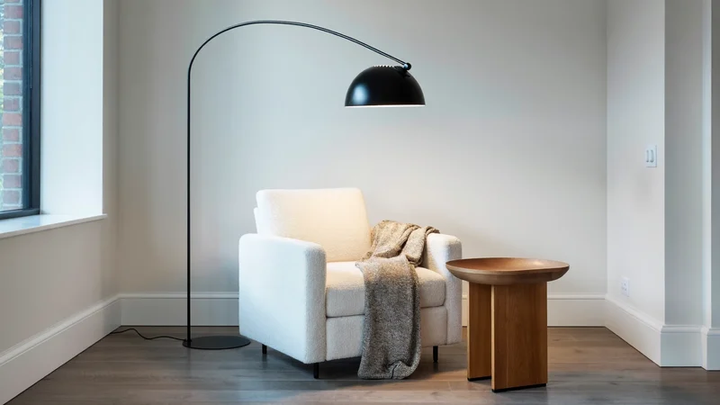 Czarna łukowa lampa podłogowa nad fotelem w kąciku do czytania